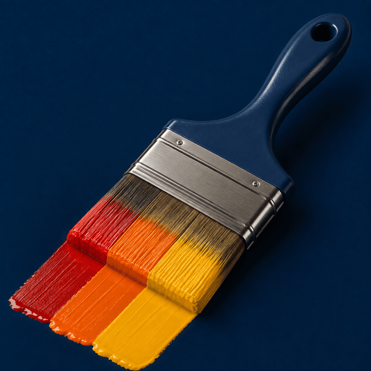 A navy-handled paintbrush with red, orange, and gold paint, inspired by the Revive logo