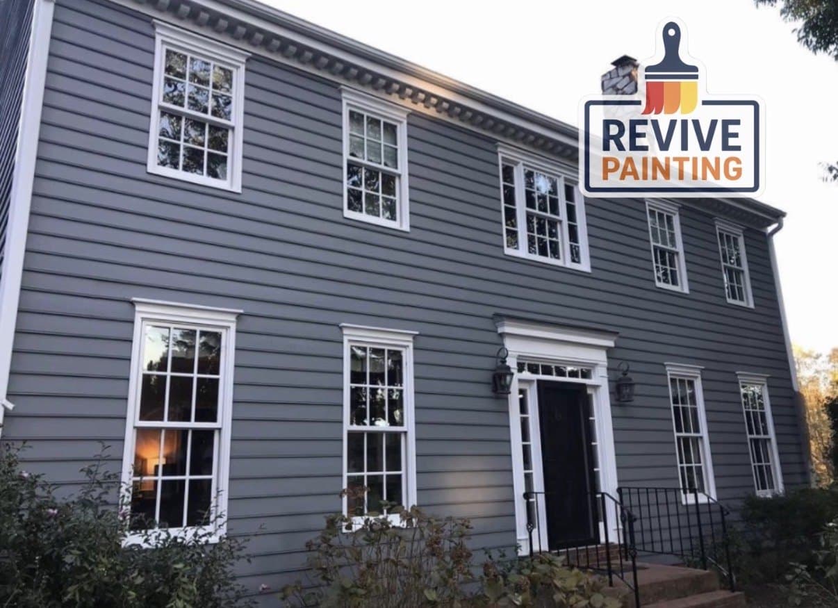 A two-story colonial with gray siding and freshly painted white trim and windows