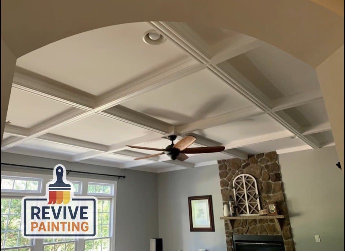 A living room coffered ceiling painted white above a stone fireplace