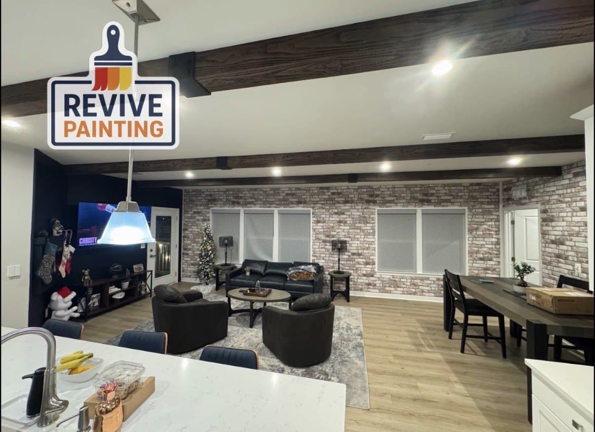 An open living room with white walls and dark painted ceiling beams