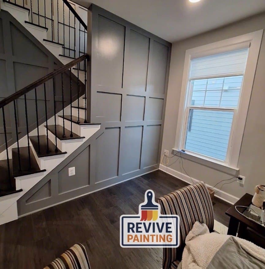 A gray board-and-batten stairwell wall with white trim and black balusters