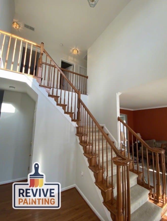 A two-story foyer repainted white with a warm wood staircase